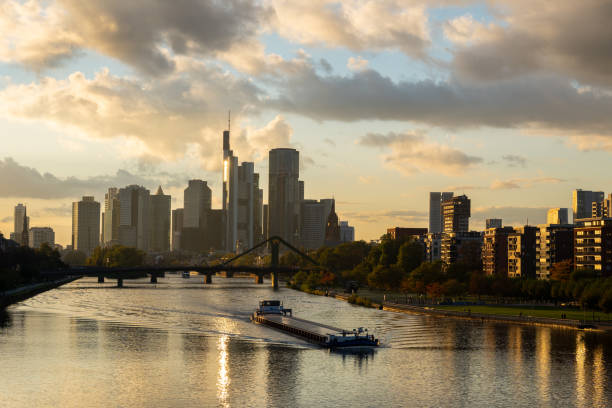Transportation Barge Travels Down the Main River with City in Background