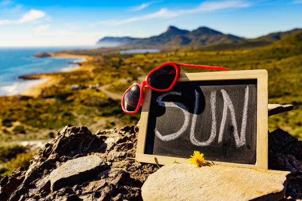 Black board with word sun against spanish sea coast. Landscape of Calblanque Park in Murcia Spain. Travel, vacation and prevention of vitamin D deficiency.