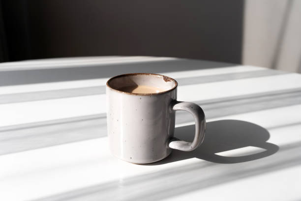 istock Ceramic Mug of Coffee or Tea Casting a Strong Shadow on a White Surface 2182316347