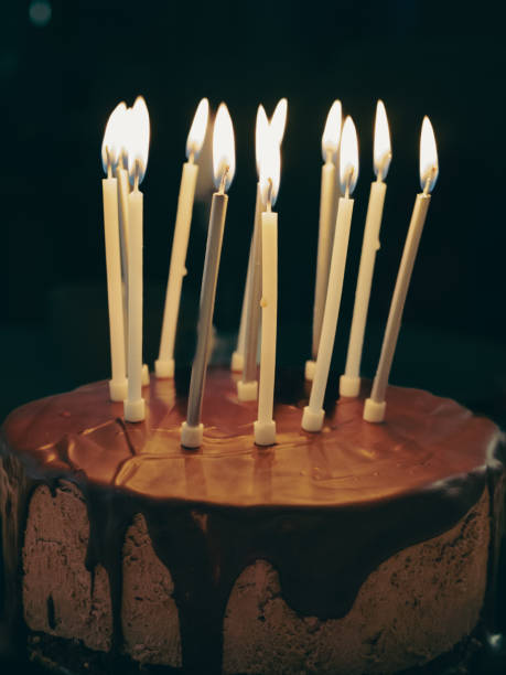 istock chocolate cake with birthday candles lit and black background 2182323531