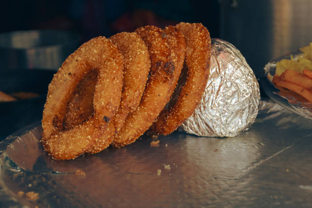 Close-up of fried onion rings with dipping sauce and lemon quarters.