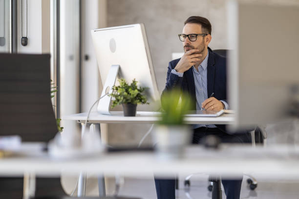 istock Focused Businessman Working at Computer Desk in Modern Office 2182329321