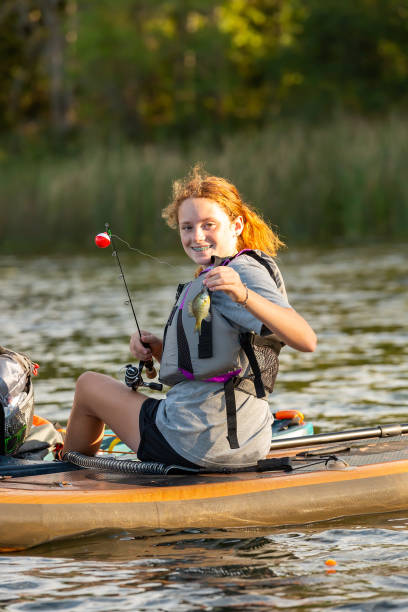 istock Girl Holding Up Fish Caught From Paddle Board 2182329507