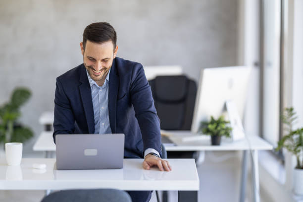 istock Smiling Businessman Engaging with Laptop in Modern Office 2182330173