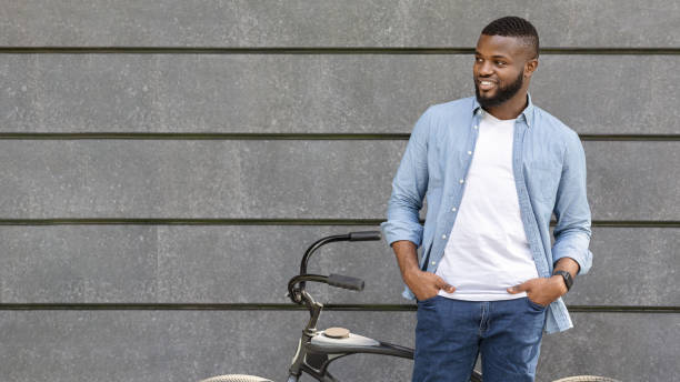 istock Handsome black man with bicycle posing over gray wall background outdoors 2182336159