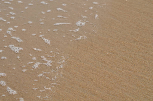 Close up of sand and wave bubbles