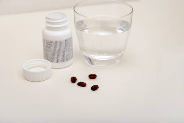 Coffee beans pill box and a glass of water, caffeine as alternative medicine.
