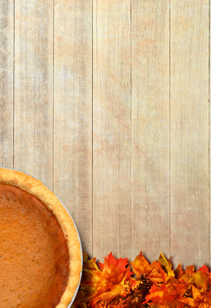 A Thanksgiving day pumpkin pie sits on a rustic wood plank surface photographed from directly above.