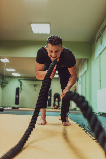 istock A fit athlete man doing intense battle rope exercise at gym. 2182349962