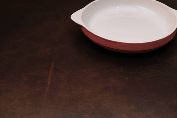 Empty white ceramic plate with grey on the down and handle on the side isolated on brown background, eating place setting.