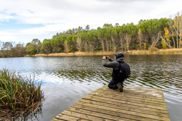 istock Man on a wooden jetty taking pictures 2182352767