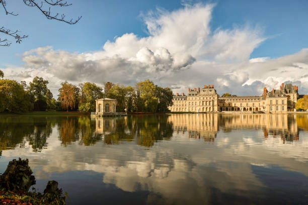Carp Lake in Chateau Fontainebleau, reflecting autumn trees under a cloudy sky