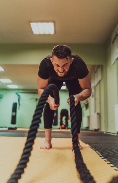 istock A fit man doing intense battle rope exercise at gym. 2182353978