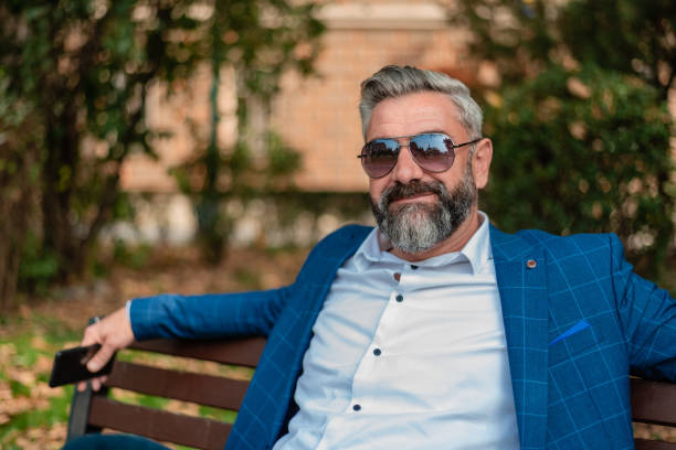 istock A happy handsome mature business man is relaxing while sitting on the park bench. 2182355470