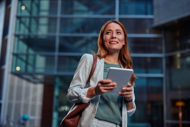 istock Confident Businesswoman Walking with Tablet in Urban Setting 2182358873
