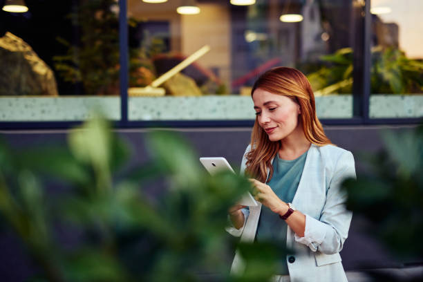 istock Businesswoman Using Tablet In Front Of The Office Building 2182359052