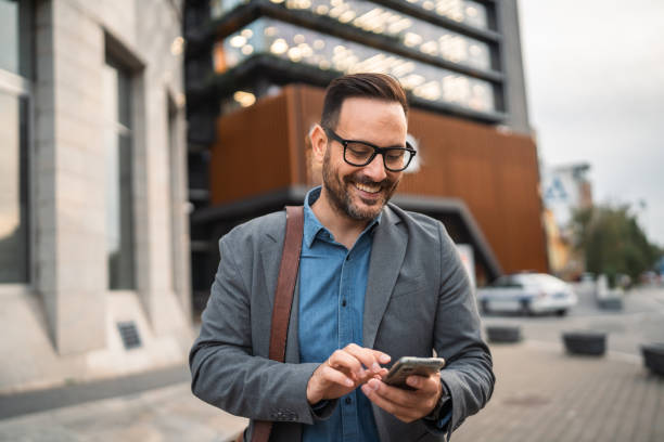 istock man businessman stand in front modern building and use mobile phone 2182360604