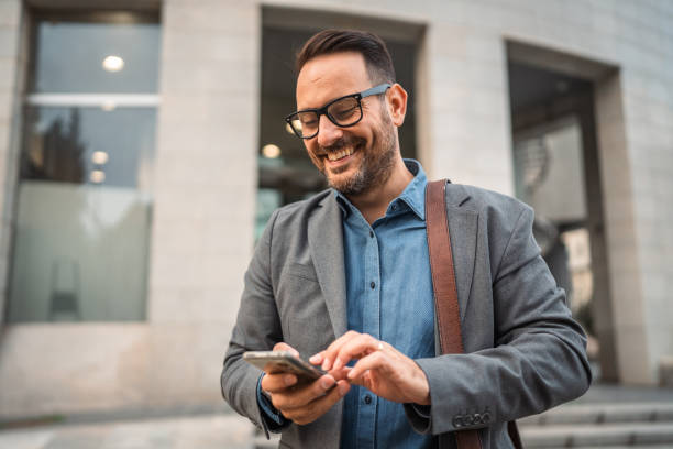 istock man businessman stand in front modern building and use mobile phone 2182360622