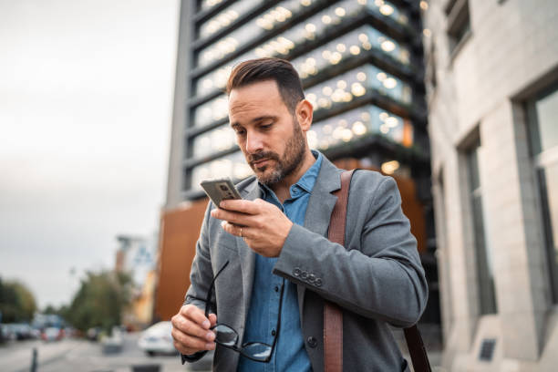 istock man businessman stand in front modern building and use mobile phone 2182361276