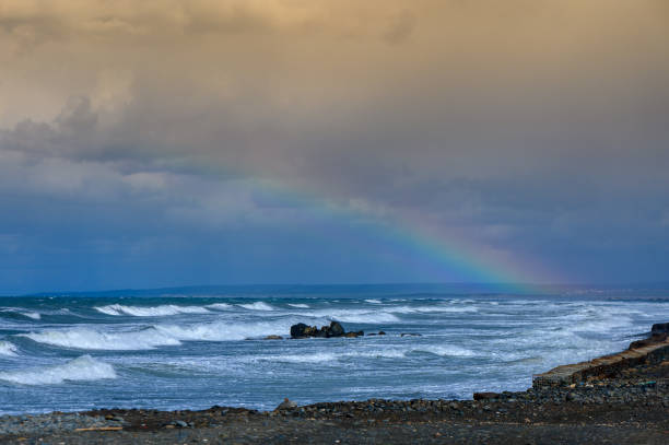 istock A breathtaking rainbow arches over the stormy ocean waves just before sunset, showcasing nature\'s vibrant colors 2182367499
