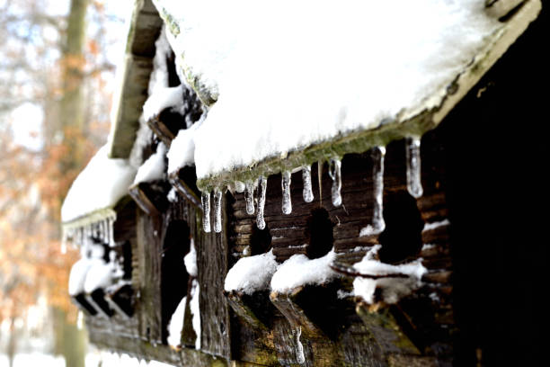 Rustic ice covered birdhouse with small icicles, vacated for winter