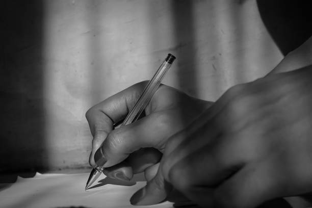Image of a person's hand writing a letter