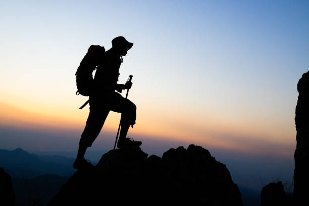 istock Silhouette of  climbers ascending a rugged mountain,  people on peak mountain climbing helping team work , travel trekking success business concept. 2182399721