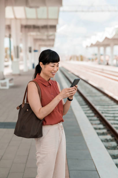 istock Asian woman waiting for a train on railway station. 2182408887