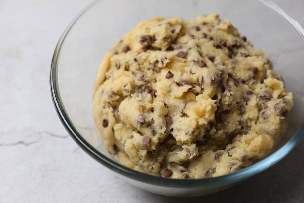 istock Chocolate chip cookie dough in glass bowl on table, closeup 2182410944