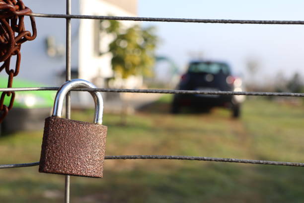 A closeup of a rusty padlock on a weathered fence, with a blurred black car in the background for contrast