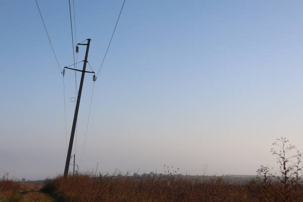 istock A Tilted Power Pole Standing Alone in an Open Field Surrounded by Natures Beauty 2182411876