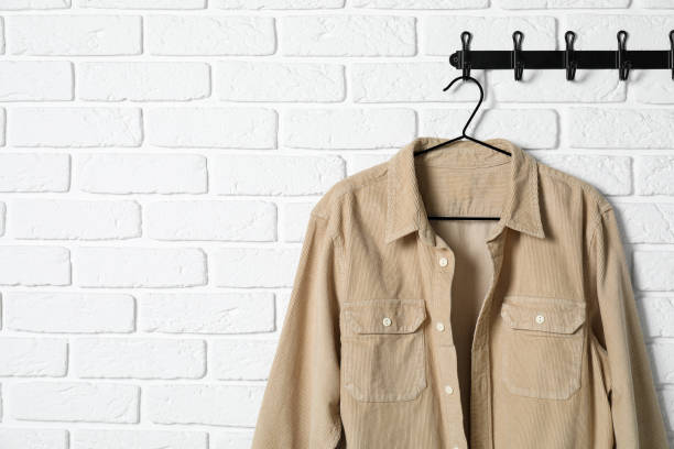 istock Hanger with beige shirt on white brick wall, space for text 2182414736