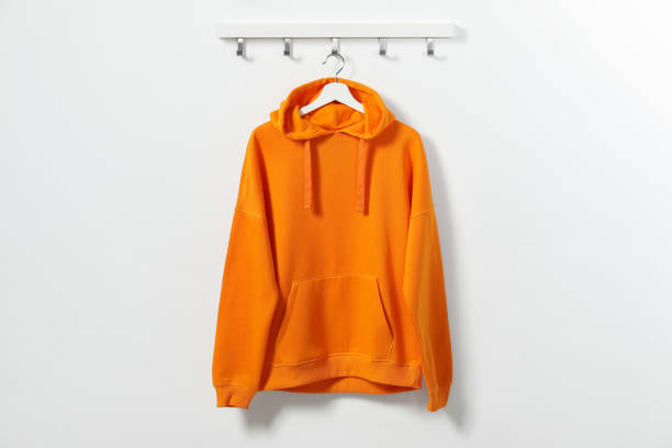 Hanger with orange hoodie on white wall