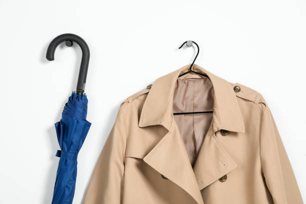 istock Hanger with beige trench coat and blue umbrella on white wall 2182414856
