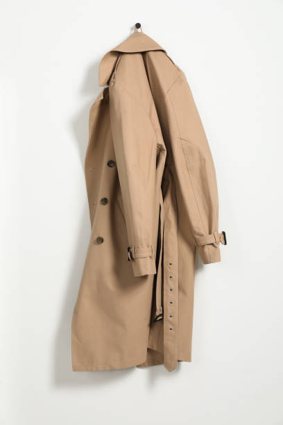 istock Beige trench coat hanging on hook rack on white wall 2182414861