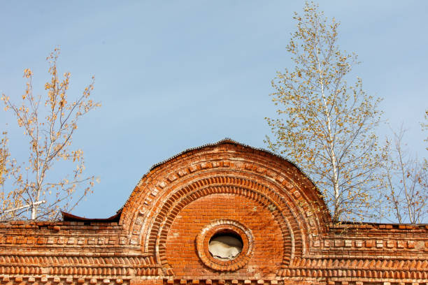A brick building with a window in the middle of the roof. The window is round and the building is old
