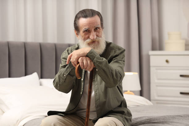 istock Senior man with walking cane on bed at home 2182419033