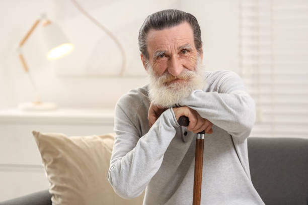 istock Senior man with walking cane on sofa at home 2182419034