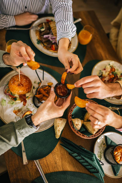 Closeup of group of people dipping french fries in ketchup. stock photo
