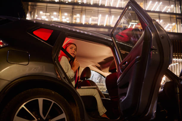istock Smiling Woman Securing Seatbelt in Car at Nighttime 2182426332