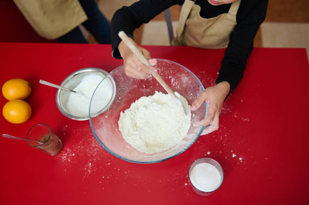 Young baker mixing ingredients for homemade cookies in kitchen