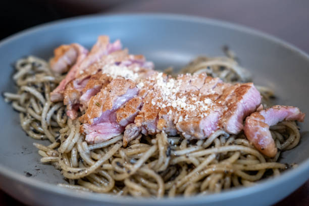 Spaghetti with truffle sauce, grilled meat on the top, served on plate