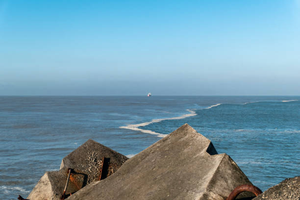 Some rocks on the dyke of Digue beach in Boucau with the sea a little rough and a boat in the background