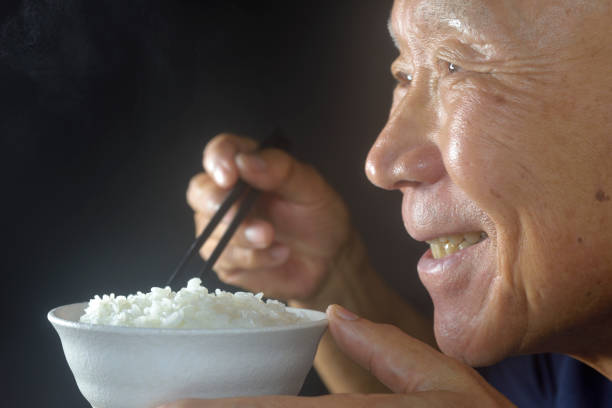 istock Smiling old man eating steaming hot rice 2182436147