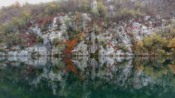 istock Rocky cliffs with autumn foliage reflected in a calm lake 2182436176