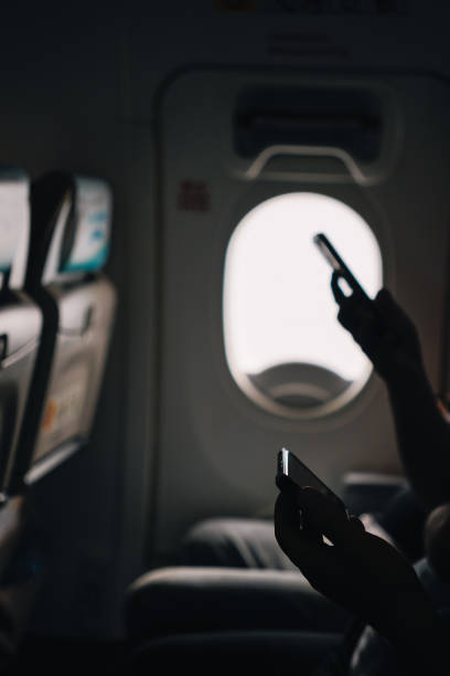 istock Hands of two unrecognizable people checking their phones on a plane 2182437992