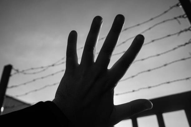 istock Cropped hand gestures against wire fence 2182445330