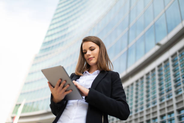 istock Businesswoman using digital tablet in front of modern office buildings 2182446559