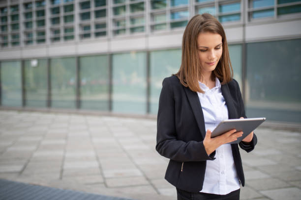 istock Businesswoman using digital tablet outside office building 2182446600