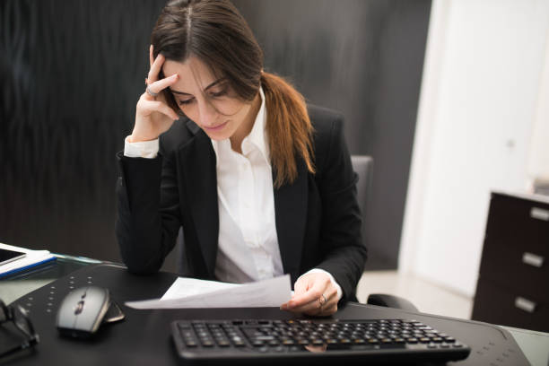 istock Stressed businesswoman reading documents at her office desk 2182448494